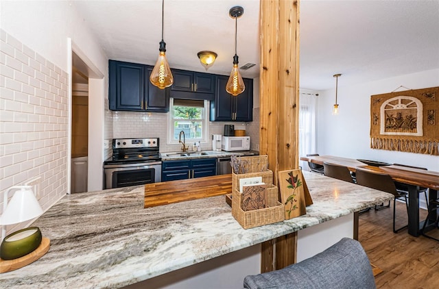 kitchen featuring kitchen peninsula, blue cabinets, stainless steel appliances, and tasteful backsplash