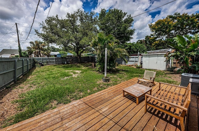 wooden terrace featuring a yard, central AC, and a storage shed