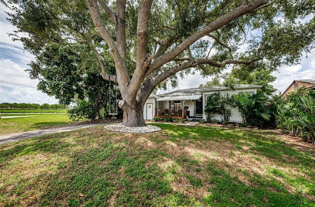 ranch-style house featuring covered porch and a front lawn