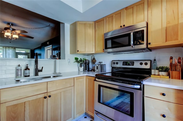 kitchen featuring ceiling fan, sink, decorative backsplash, light brown cabinetry, and appliances with stainless steel finishes