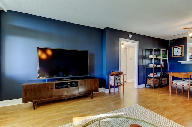 living room featuring a textured ceiling, light wood-type flooring, and ceiling fan