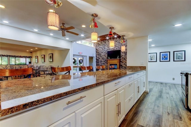 kitchen with dark hardwood / wood-style flooring, electric stove, decorative light fixtures, dark stone countertops, and white cabinets