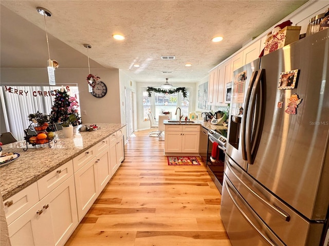 kitchen featuring pendant lighting, white cabinets, and stainless steel appliances