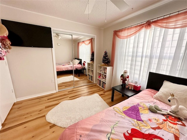 bedroom featuring multiple windows, ceiling fan, a closet, and wood-type flooring