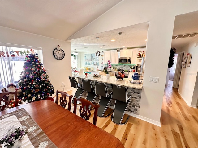 dining area with light hardwood / wood-style flooring and lofted ceiling