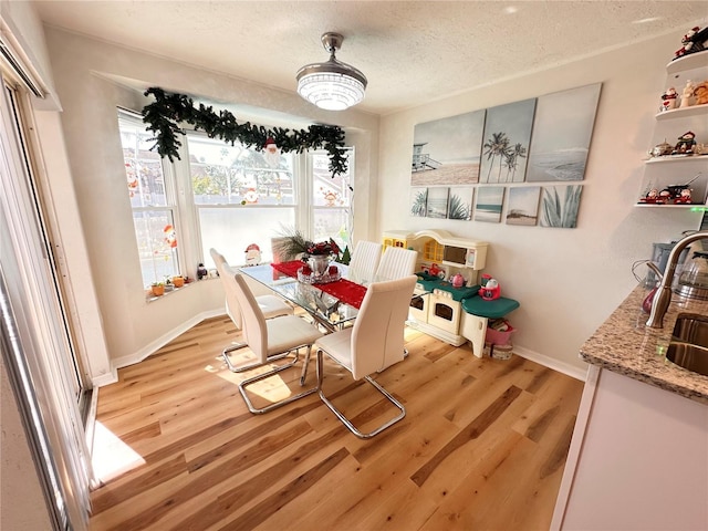 dining space with a textured ceiling, light hardwood / wood-style floors, and sink