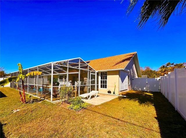 back of house with a yard, glass enclosure, a patio area, and a swimming pool