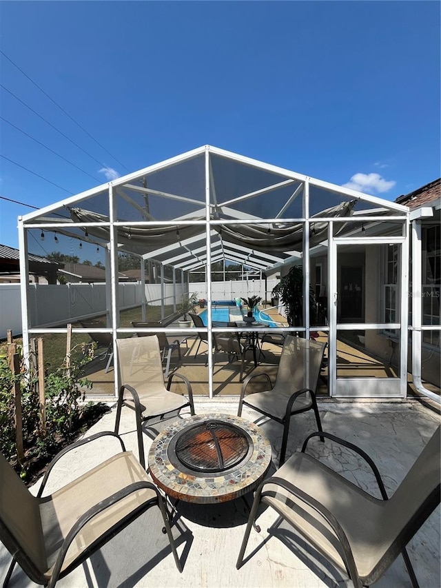 view of patio / terrace with a swimming pool, an outdoor fire pit, glass enclosure, and a fenced backyard