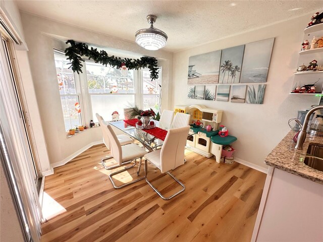 dining room with a textured ceiling, baseboards, and light wood-type flooring