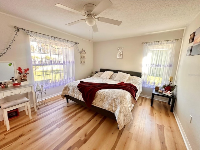 bedroom featuring a textured ceiling, light wood-style floors, ceiling fan, and baseboards