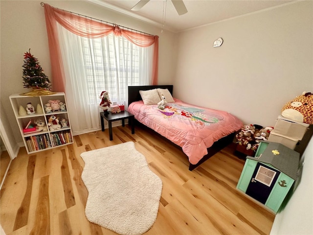 bedroom with crown molding, a ceiling fan, and wood finished floors
