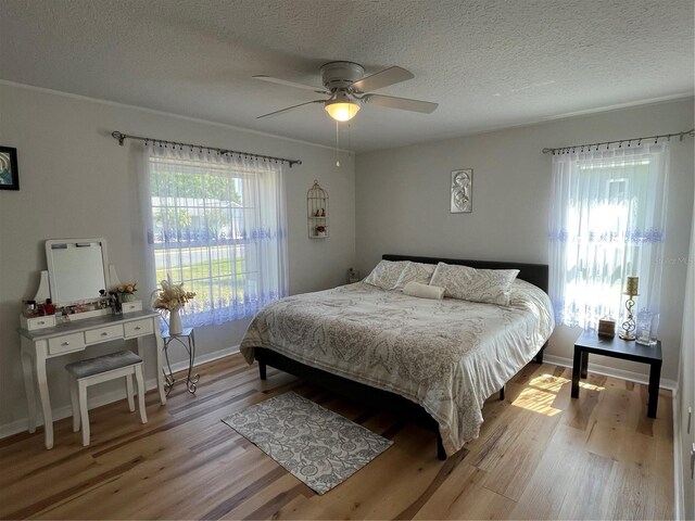 bedroom featuring baseboards, ceiling fan, a textured ceiling, and light wood-style flooring