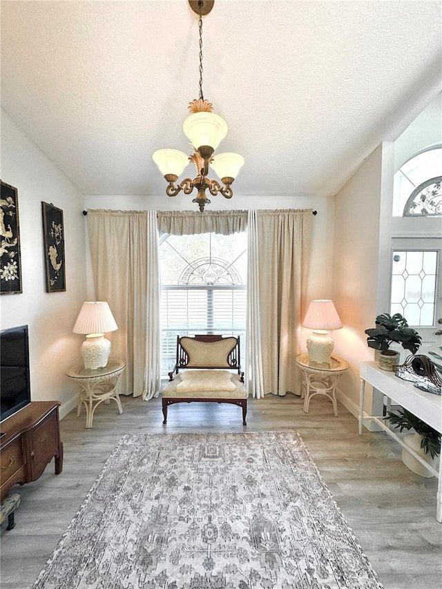 sitting room with hardwood / wood-style floors, a textured ceiling, and a chandelier