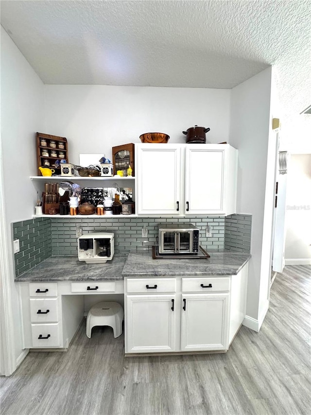 interior space with light stone countertops, light hardwood / wood-style floors, a textured ceiling, and white cabinets