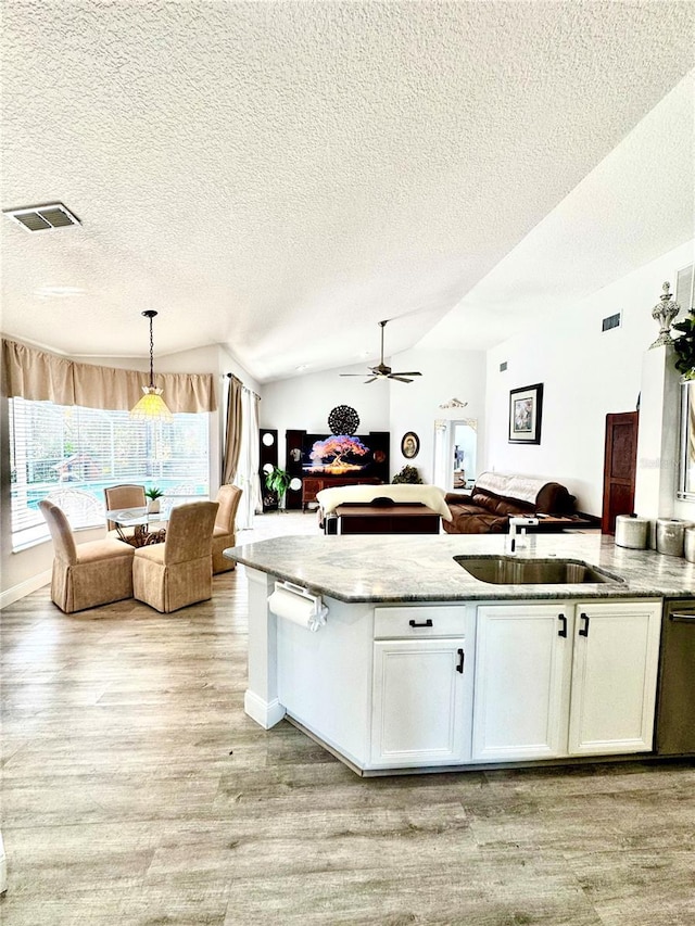 kitchen featuring sink, white cabinetry, hanging light fixtures, a textured ceiling, and stainless steel dishwasher