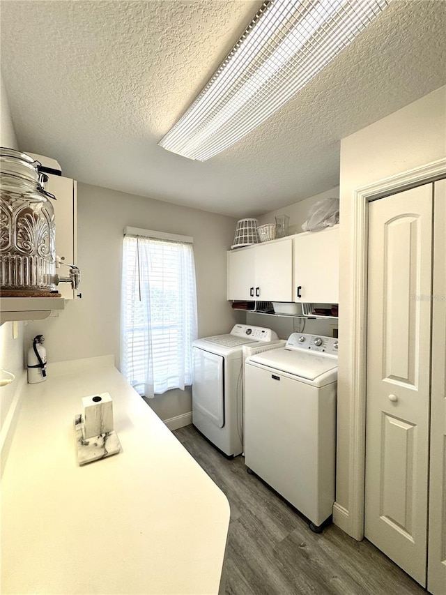 washroom with a textured ceiling, wood finished floors, washing machine and dryer, cabinet space, and baseboards