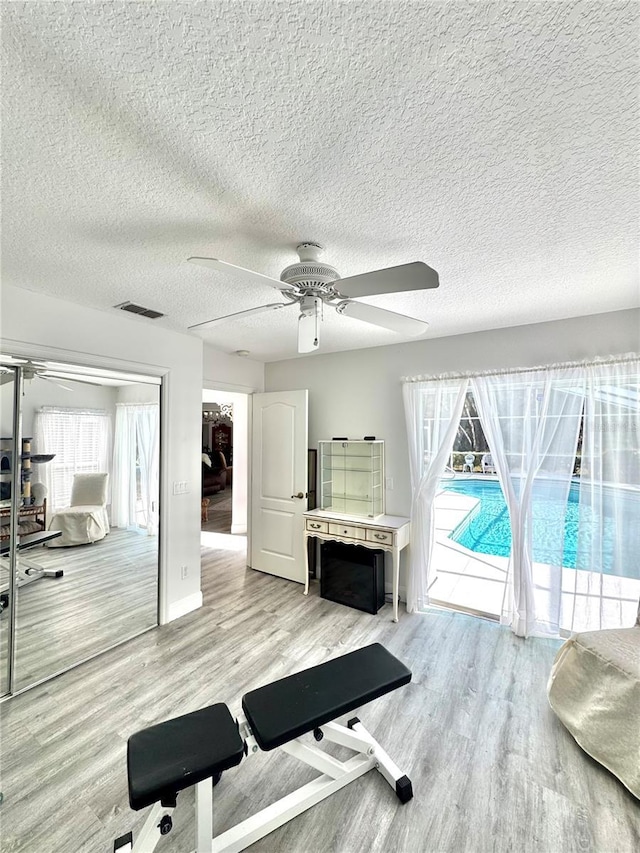 exercise area with light hardwood / wood-style flooring and ceiling fan