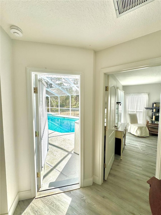 doorway featuring a wealth of natural light, a textured ceiling, and light wood-type flooring