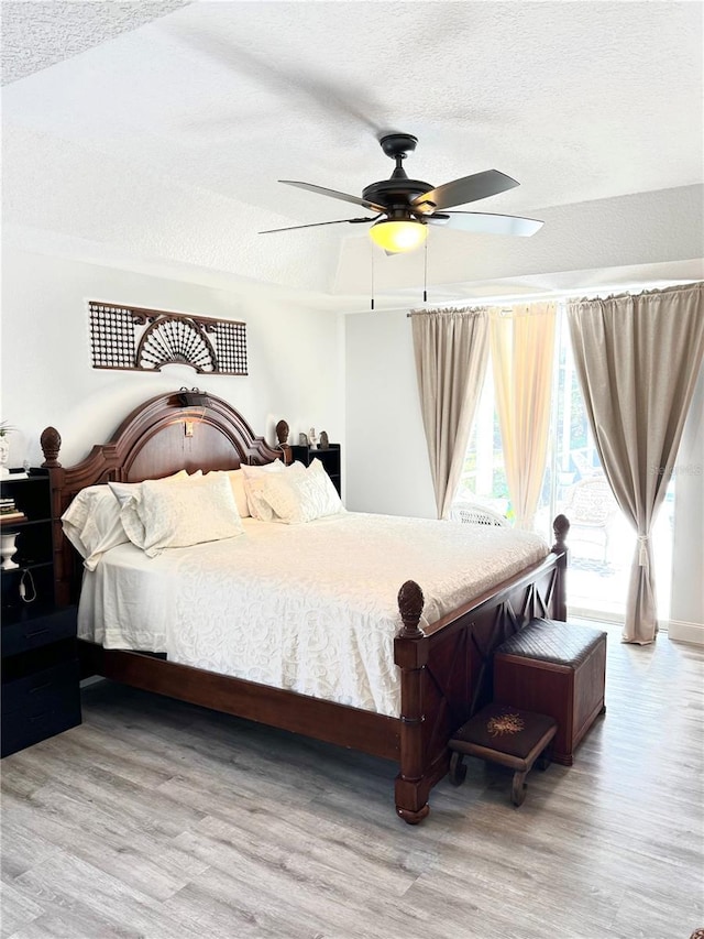 bedroom with ceiling fan, light hardwood / wood-style floors, and a textured ceiling