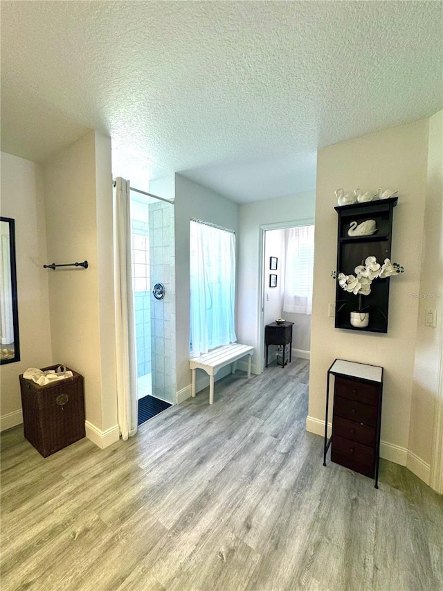 bathroom with wood-type flooring, a shower, and a textured ceiling