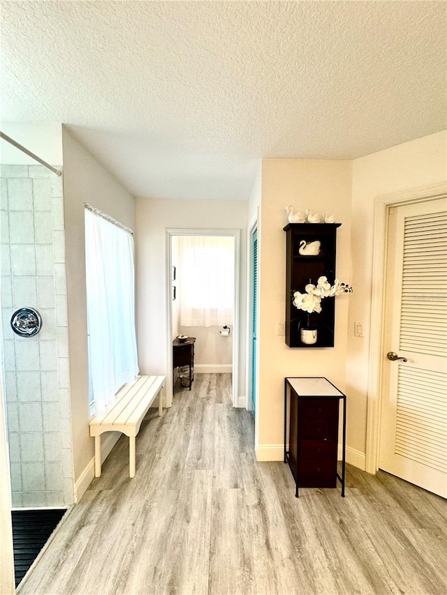 hall with light hardwood / wood-style flooring and a textured ceiling