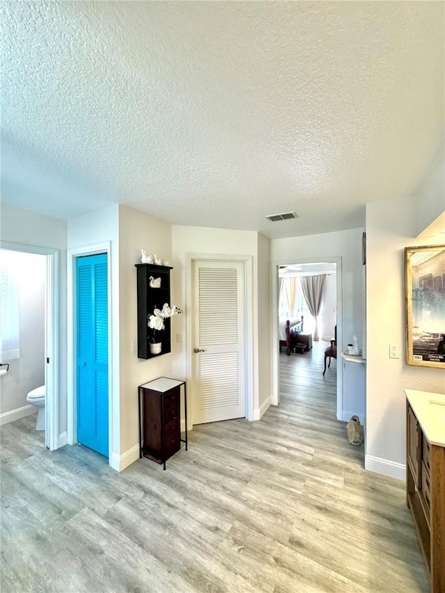 hall featuring a textured ceiling and light hardwood / wood-style flooring