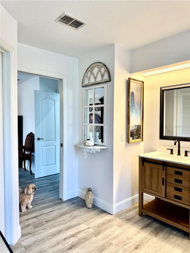 hall featuring sink, a textured ceiling, and light wood-type flooring