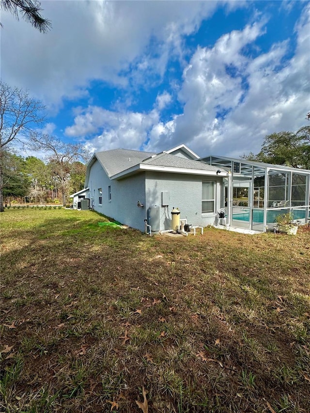 rear view of house with a lanai and a yard