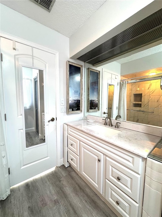 bathroom with vanity, hardwood / wood-style floors, curtained shower, and a textured ceiling