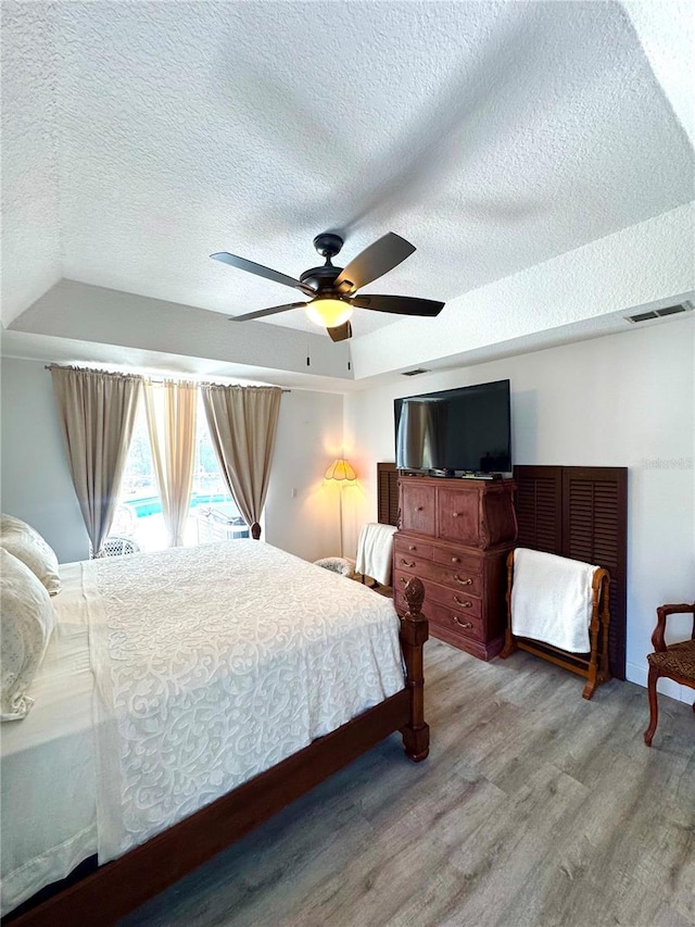 bedroom featuring ceiling fan, a textured ceiling, and light hardwood / wood-style flooring