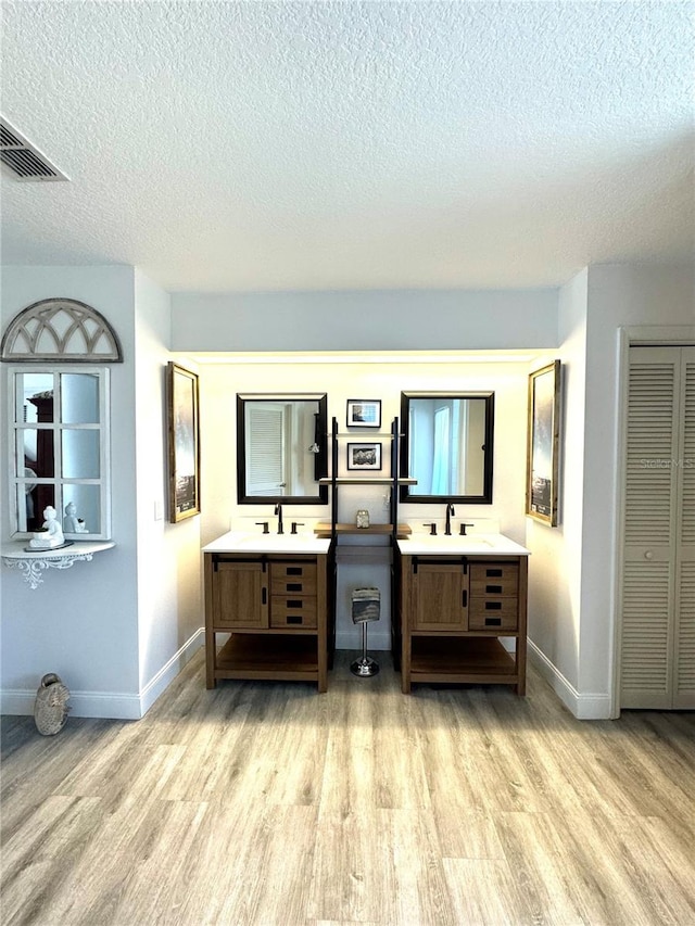 interior space featuring vanity, hardwood / wood-style floors, and a textured ceiling