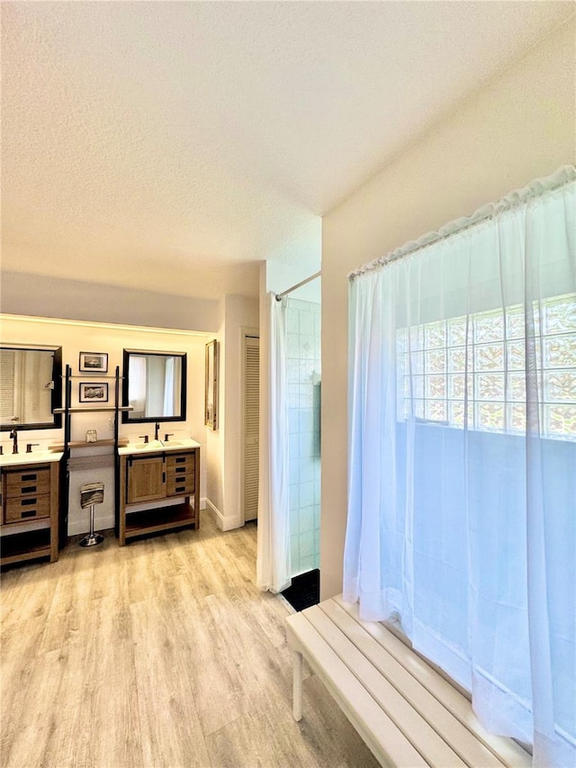 bathroom featuring vanity, hardwood / wood-style floors, a textured ceiling, and walk in shower