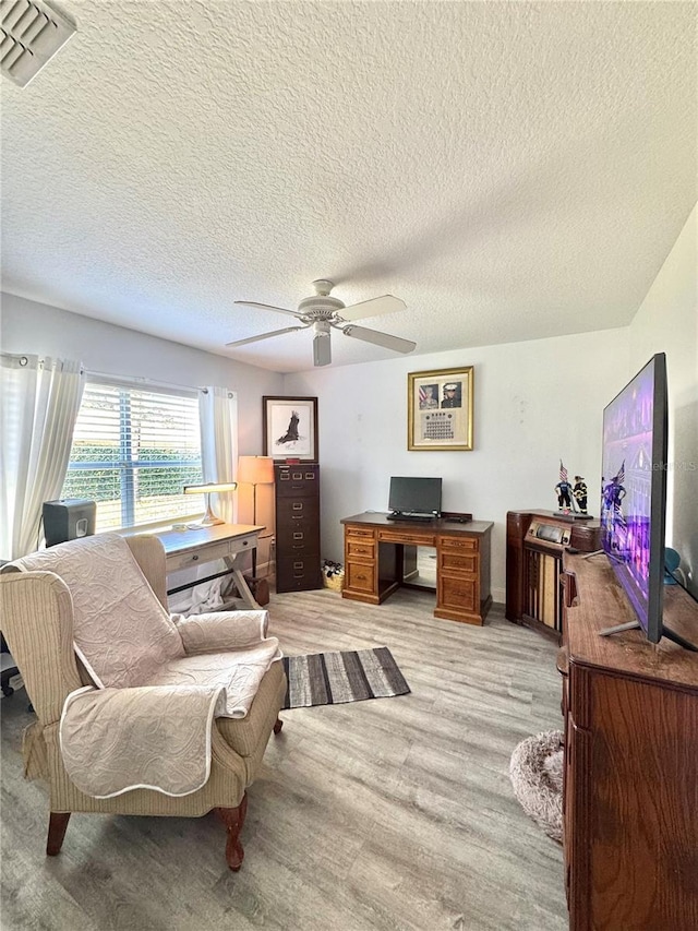 office space featuring visible vents, light wood-type flooring, and a ceiling fan