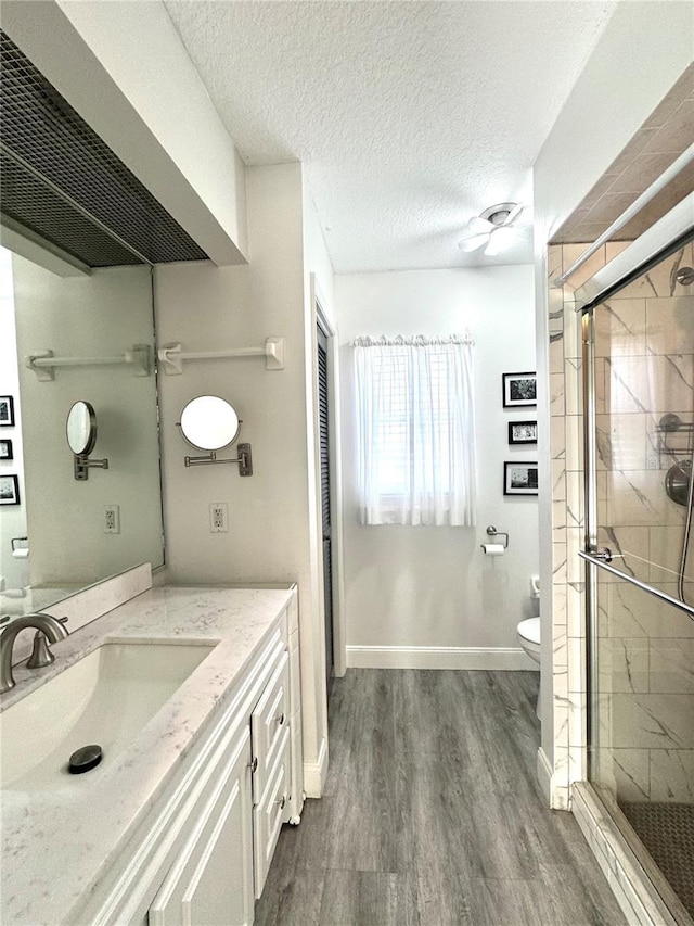 full bathroom featuring a shower stall, toilet, wood finished floors, and a textured ceiling