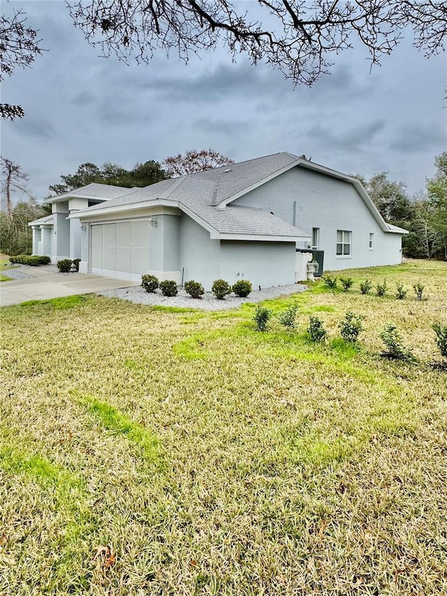 view of property exterior featuring a lawn, an attached garage, driveway, and stucco siding