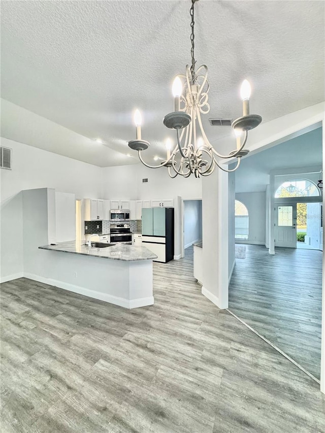 kitchen with visible vents, light wood-style flooring, decorative backsplash, white cabinets, and appliances with stainless steel finishes