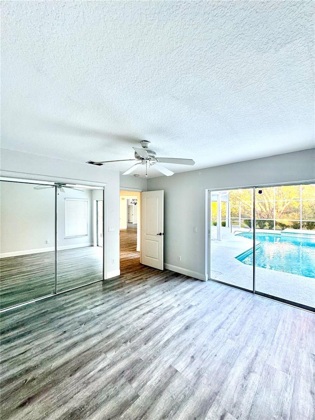 unfurnished bedroom featuring access to exterior, baseboards, wood finished floors, a closet, and a ceiling fan