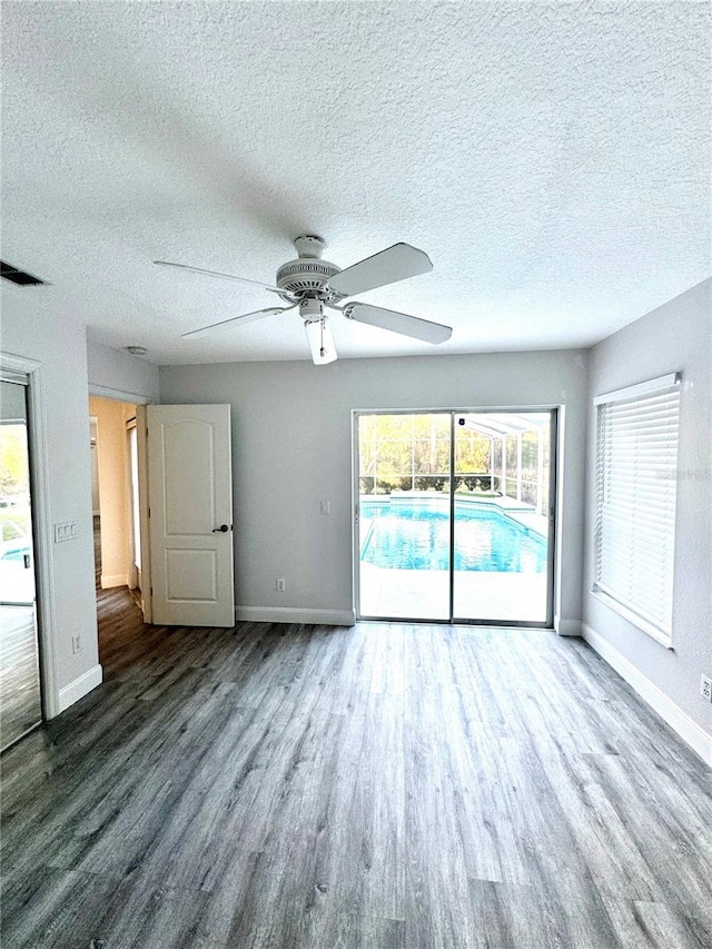 spare room featuring a ceiling fan, wood finished floors, baseboards, and a textured ceiling