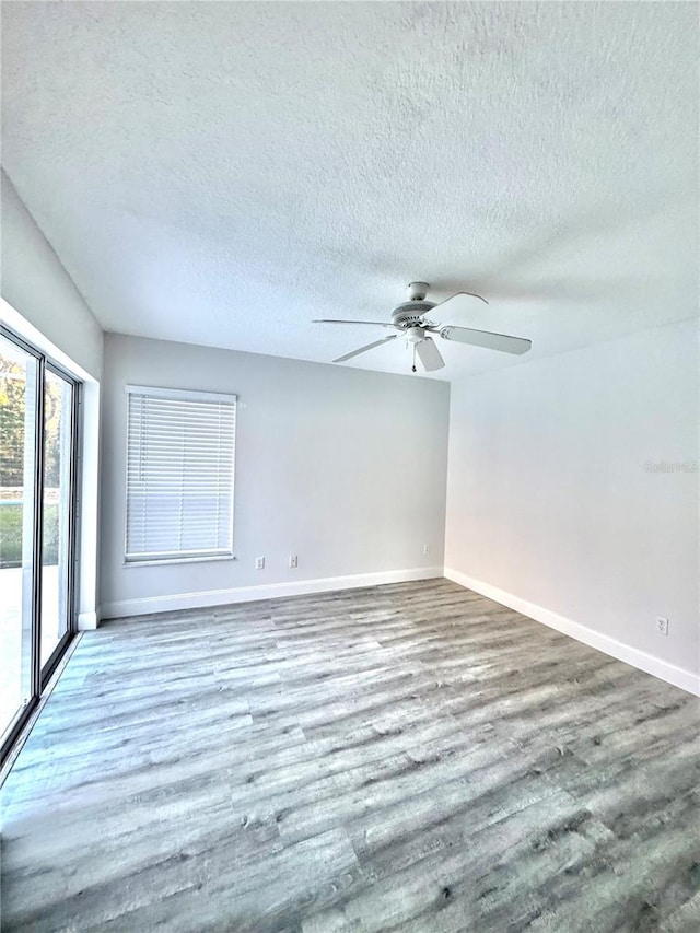 spare room featuring a ceiling fan, wood finished floors, baseboards, and a textured ceiling