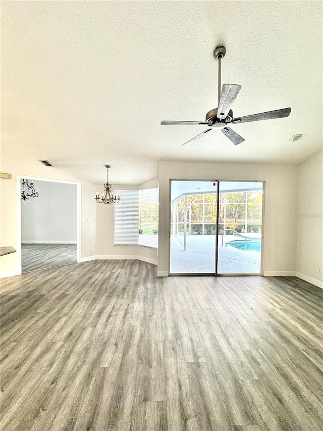 unfurnished room featuring visible vents, a textured ceiling, baseboards, and wood finished floors