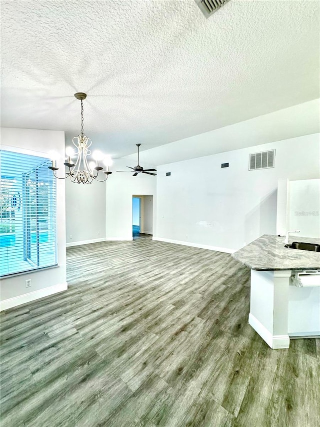 unfurnished living room featuring visible vents, a sink, a textured ceiling, wood finished floors, and baseboards