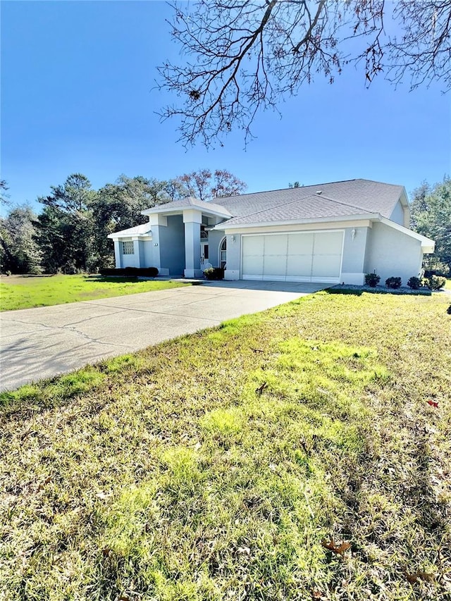 view of front facade featuring stucco siding, driveway, a garage, and a front yard