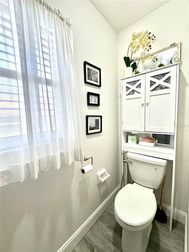 bathroom featuring toilet, wood finished floors, baseboards, and a textured ceiling