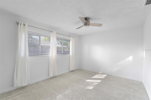 empty room with ceiling fan, light colored carpet, and a textured ceiling