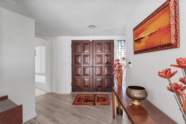 foyer entrance featuring a textured ceiling and light hardwood / wood-style flooring