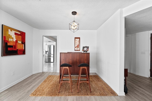 dining room featuring hardwood / wood-style flooring, an inviting chandelier, and a textured ceiling