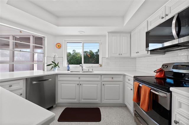 kitchen with sink, decorative backsplash, white cabinets, and appliances with stainless steel finishes