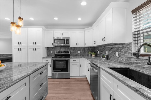 kitchen featuring sink, tasteful backsplash, white cabinetry, wood-type flooring, and stainless steel appliances