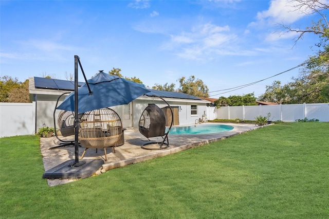 back of property with solar panels, a yard, a fenced in pool, and a patio area