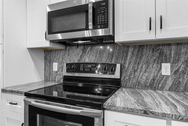 kitchen featuring dark stone countertops, white cabinetry, and stainless steel appliances